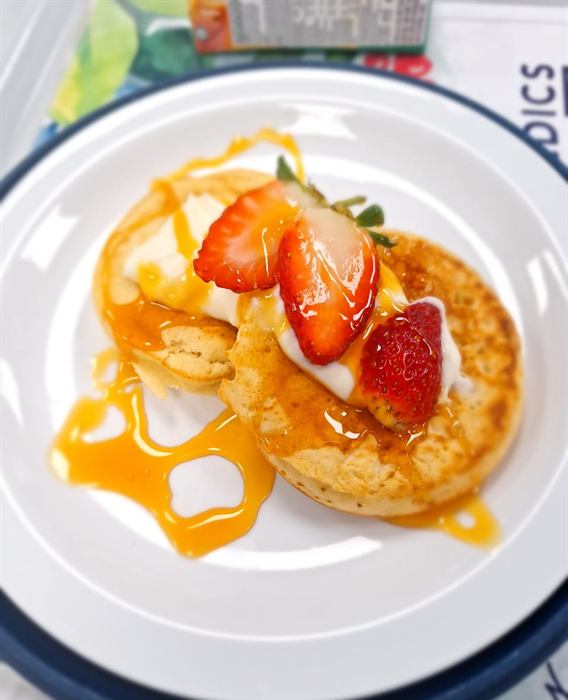 Stacked pancakes with cream, fresh strawberries and a caramel drizzle