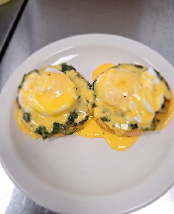 Two poached eggs on spinach-topped muffins under hollandaise