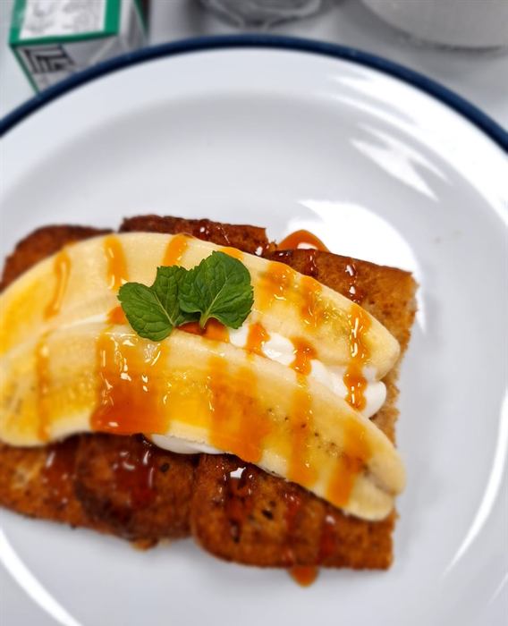 French toast with sliced banana, cream and a caramel drizzle