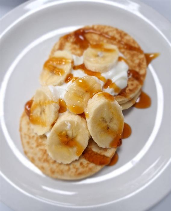 Pancakes topped with cream, sliced banana and caramel