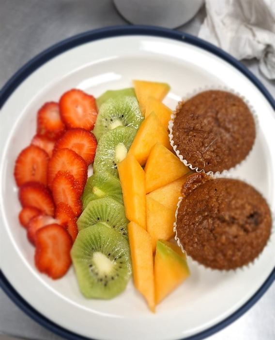 Sliced strawberries, kiwi and melon plated with two bran muffins