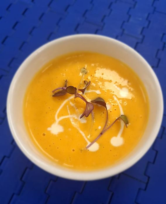 Smooth butternut soup finished with a cream swirl and micro herbs
