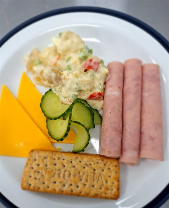 Cold plate of rolled ham, potato salad, cheese, cucumber and crackers