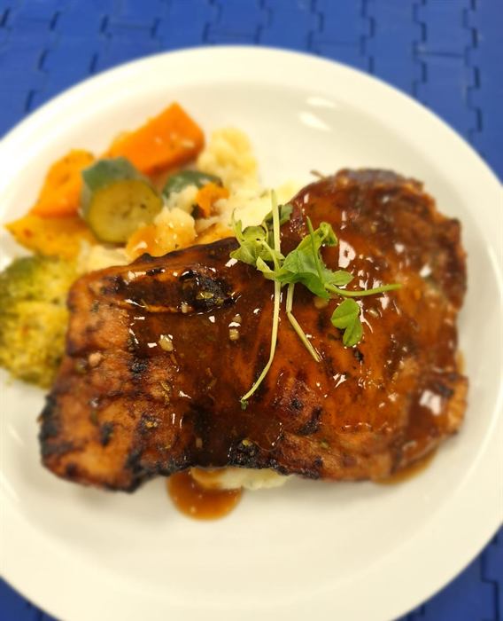 Dark sticky glazed ribs finished with micro herbs, with mash and buttered mixed vegetables