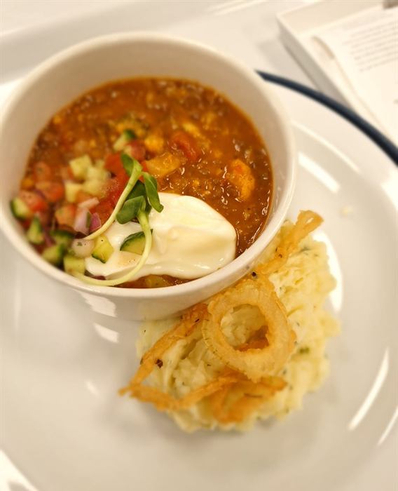 Bean and vegetable stew with sour cream and fresh salsa, alongside a potato rosti