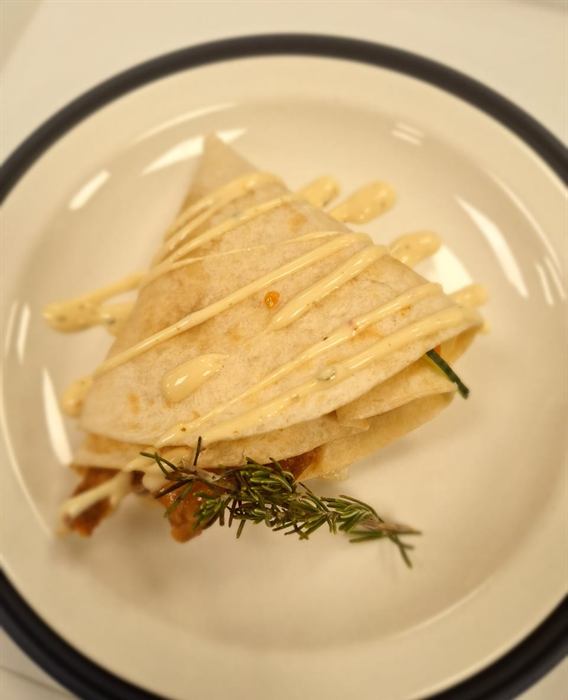 Quesadilla cut into wedges and fanned across the plate with rosemary