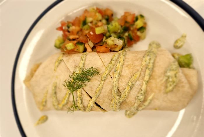 Burrito finished with a herb drizzle and a spoonful of fresh tomato salsa