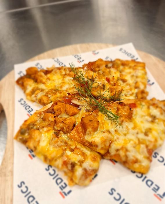 Squares of thin-base pizza with cheese, ham and herbs