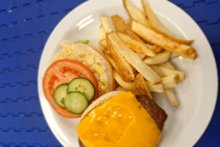 Open cheeseburger with melted cheese, tomato and cucumber, served with chips