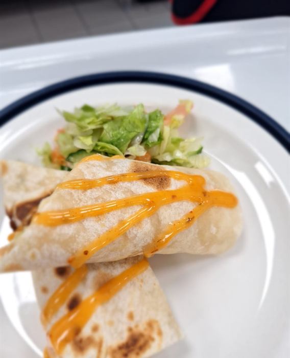 Wraps under a cheese-sauce drizzle with shredded lettuce