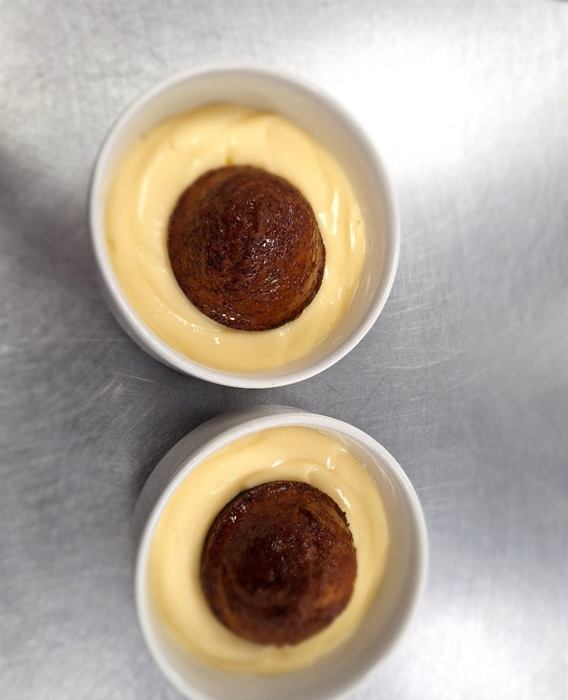 Two malva puddings in shallow bowls of custard
