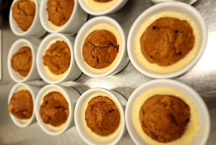 A tray of baked puddings resting in custard