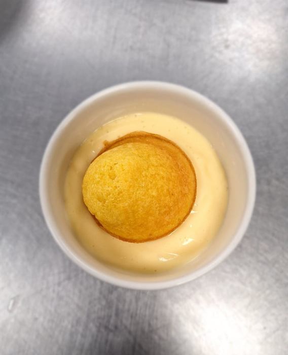 A sponge pudding sitting in custard