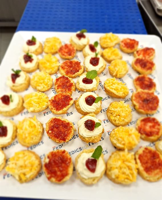 A tray laid out in a grid of assorted canapes with piped toppings