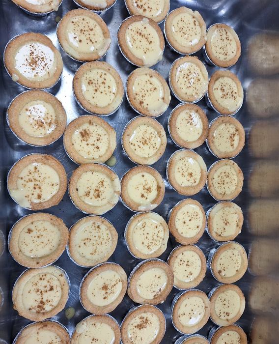 Dozens of identical tartlets lined up across a tray