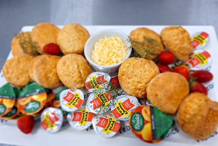 A platter of croquettes and muffins with butter, cheese and preserves